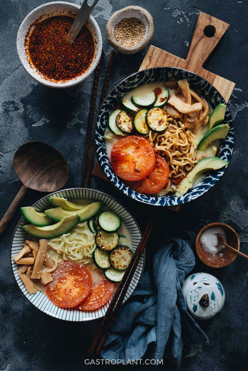 Two bowls of light creamy soy milk ramen noodle soup with avocado and tomato