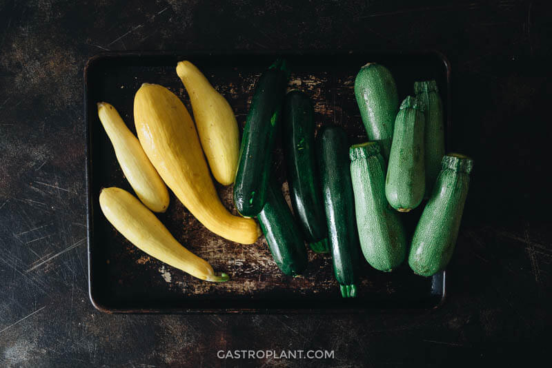 Fresh yellow, gray, and zucchini squash on a metal tray