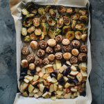 Roasted potatoes, mushrooms, and brussels sprouts on a sheet pan with parchmen