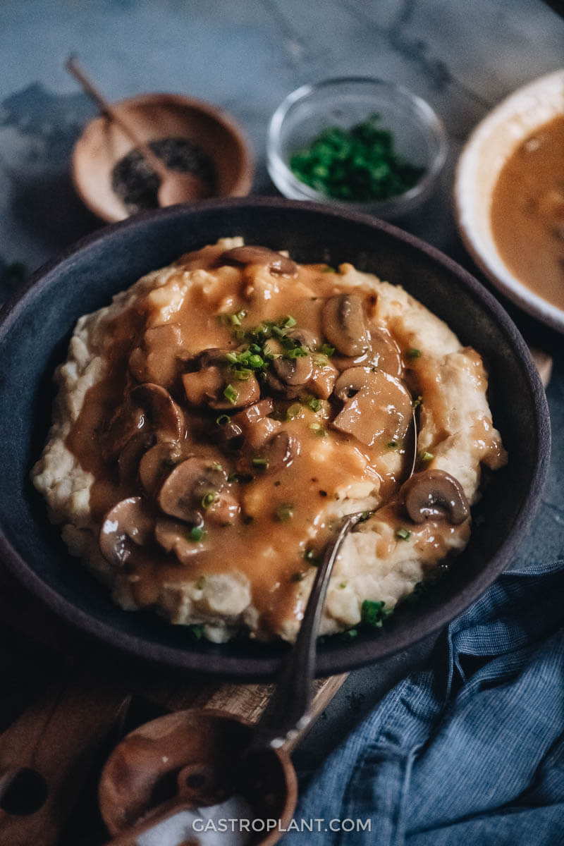 A bowl of mashed potatoes topped with vegan brown mushroom gravy