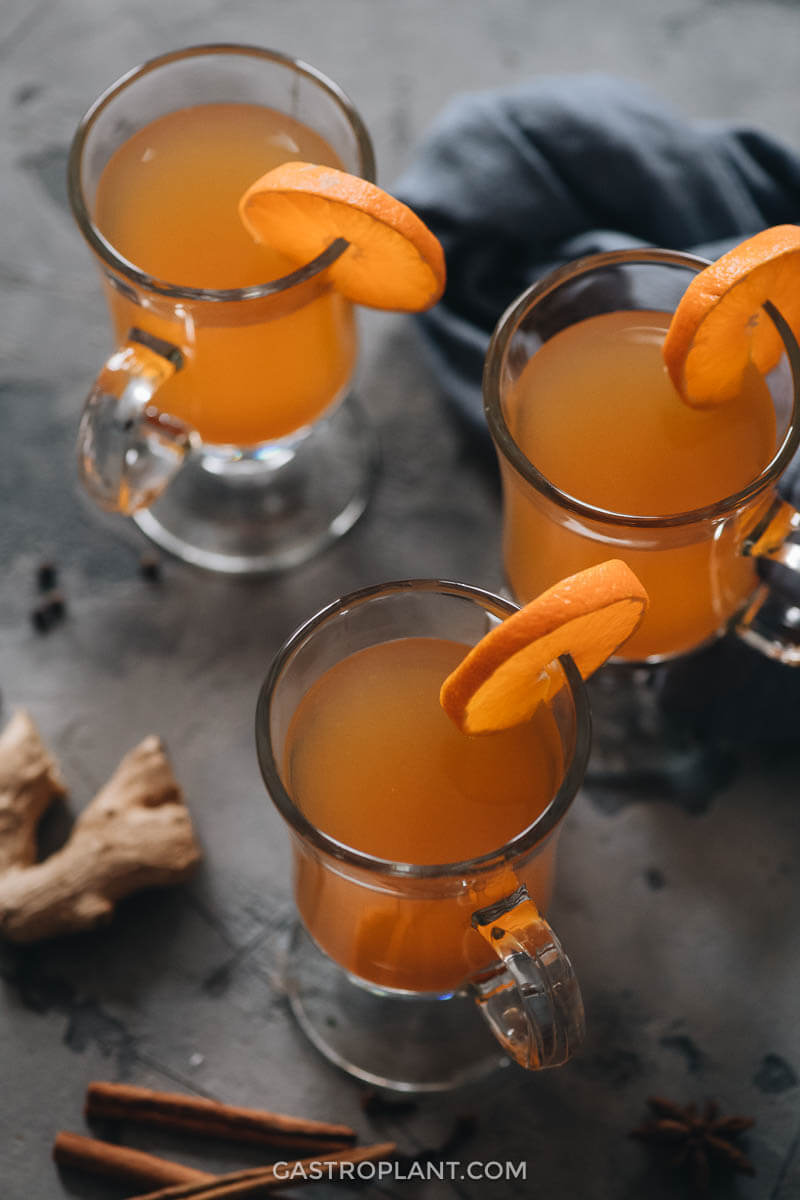 Close up of mulled apple cider in glasses with orange slice garnish