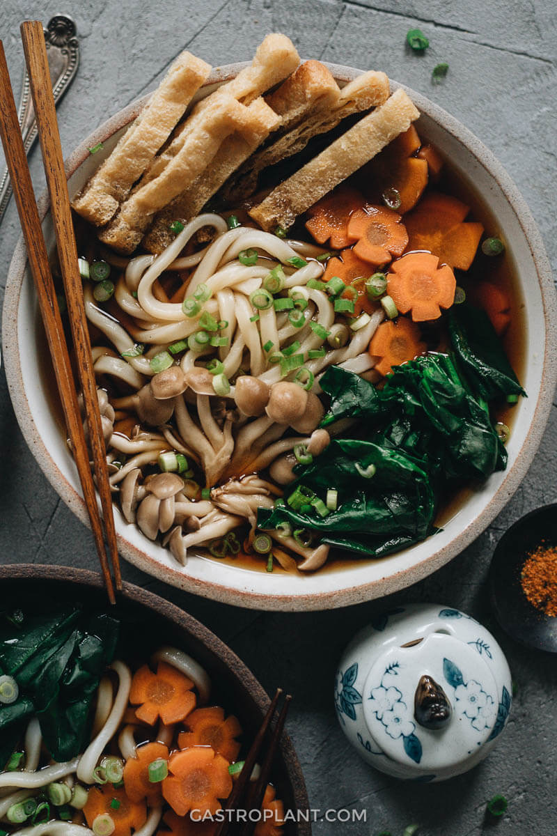 Vegan udon noodle soup with mushroom, carrot, tofu, and spinach