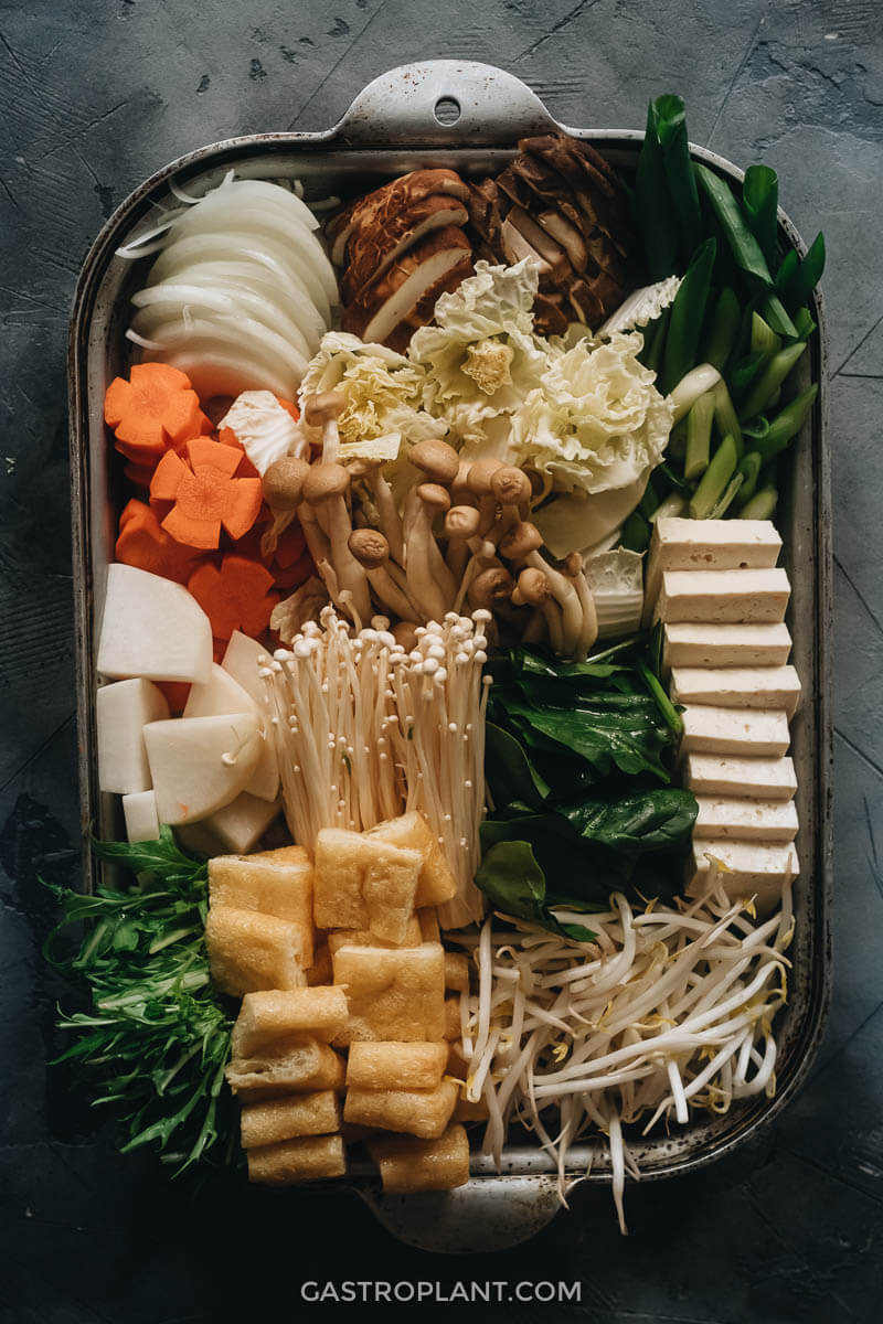 A tray full of mushrooms, tofu, aburaage, and vegetables for hot pot