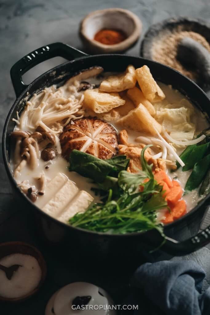 A pot of vegetables, mushrooms, and tofu in a savory soy milk broth