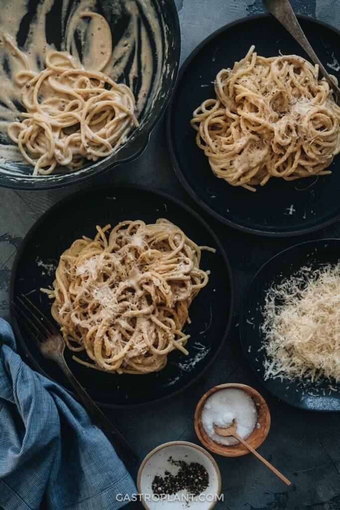 Servings of creamy black pepper vegan pasta on black plates