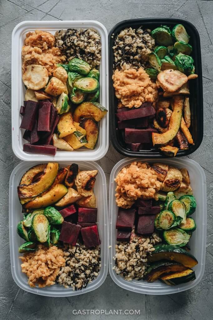 Four meal prep containers packed with vegan lunches