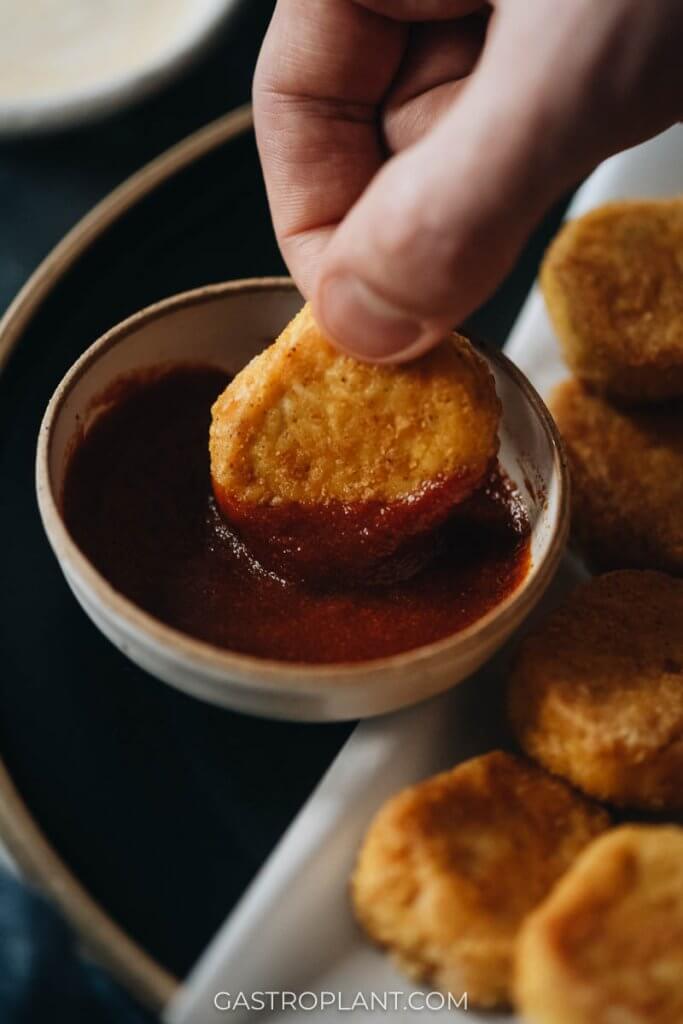 Dipping a vegan chicken nugget in curry ketchup