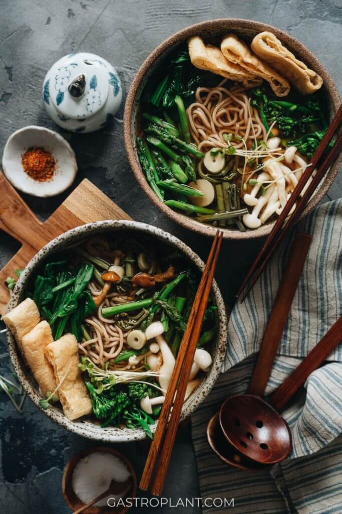 Two bowls of vegan sansai soba noodle soup with fresh spring vegetables