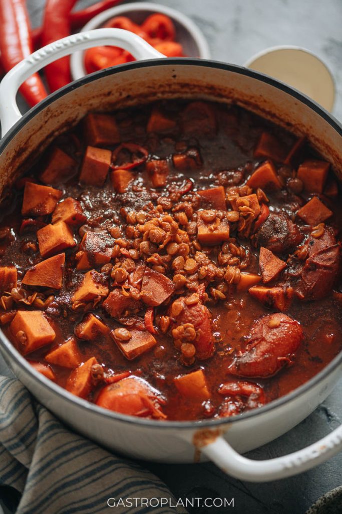 A hearty pot of chili with lentils, sweet potatoes, and tomatoes in a spicy, smoky broth