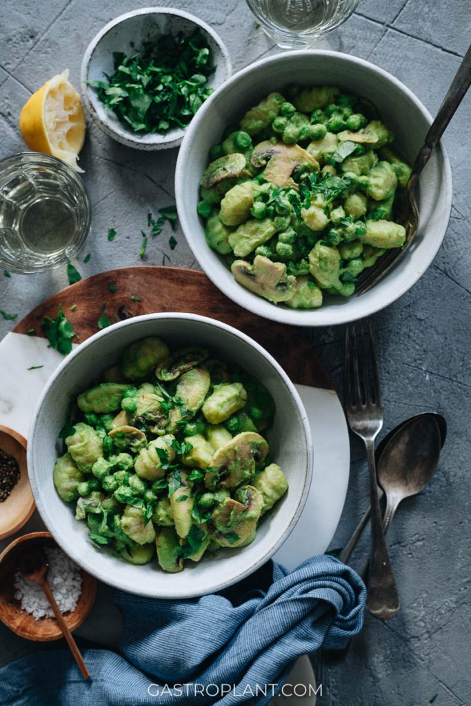 Two bowls of green pea pasta (gnocchi) with peas and mushrooms and lemon