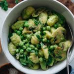 A bowl of gnocchi coated in green pea pasta sauce