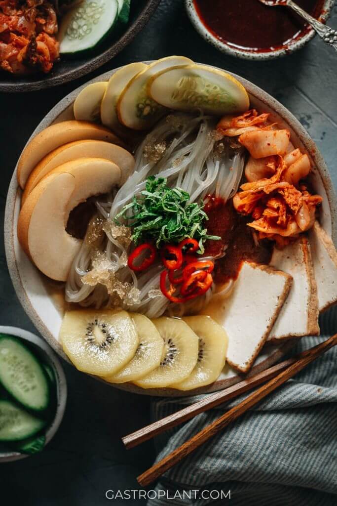 Vegan Korean cold noodles with kimchi, Asian pear, kiwi and tofu