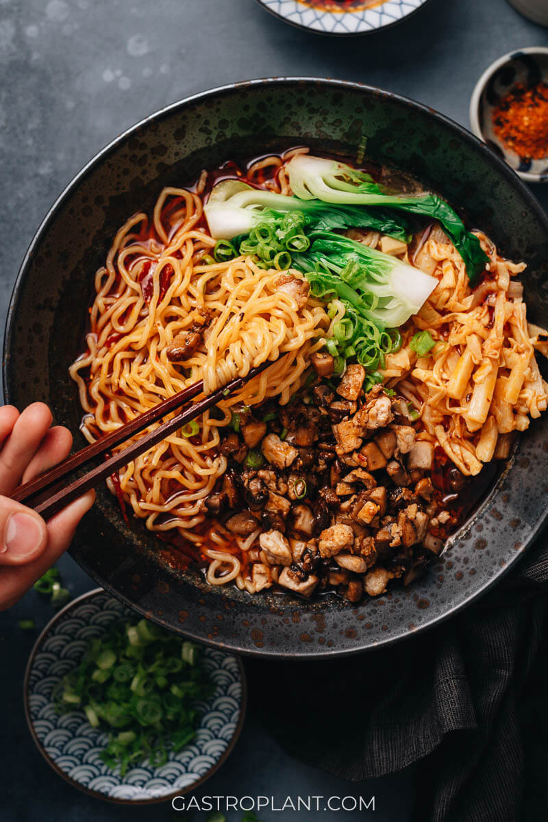 A hot bowl of sizzling spicy ramen noodle soup with bamboo, tofu, and mushrooms