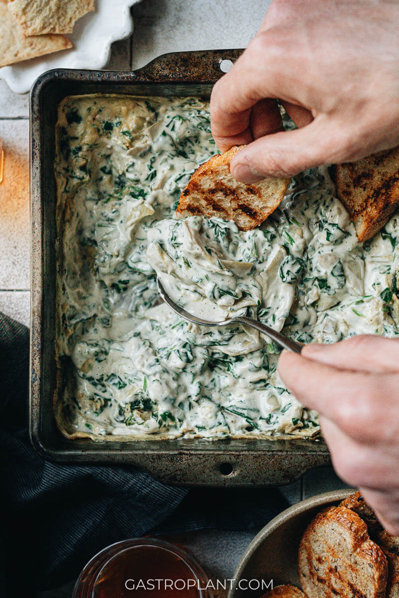 Close-up of scooping vegan spinach artichoke dip