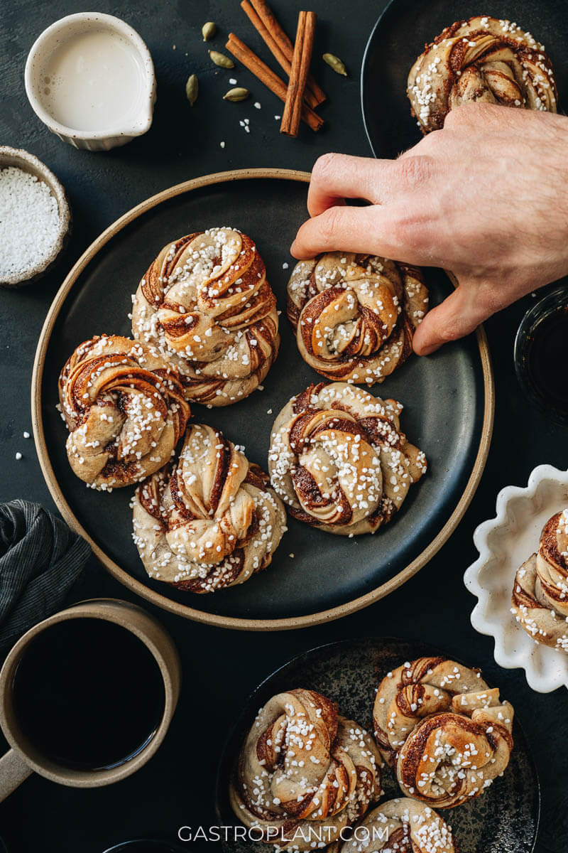 A hand reaching for a Scandinavian style cinnamon bun