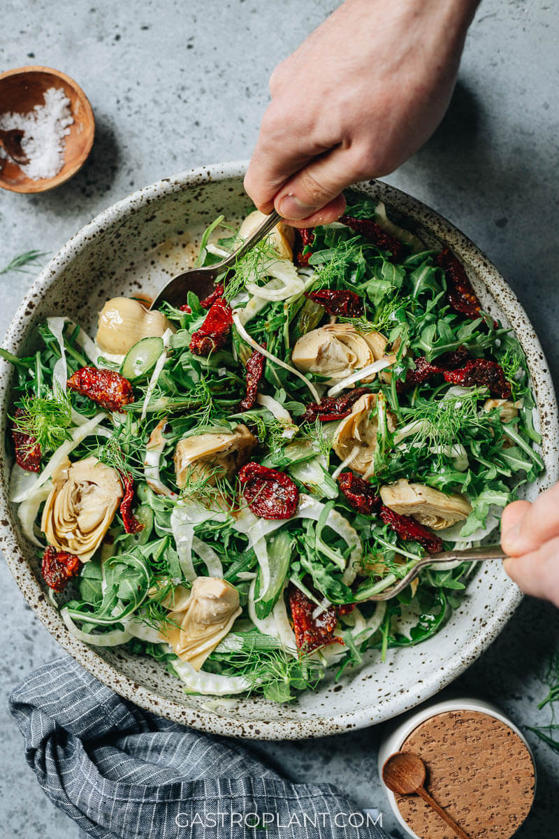 Tossing a bowl of Italian inspired arugula salad