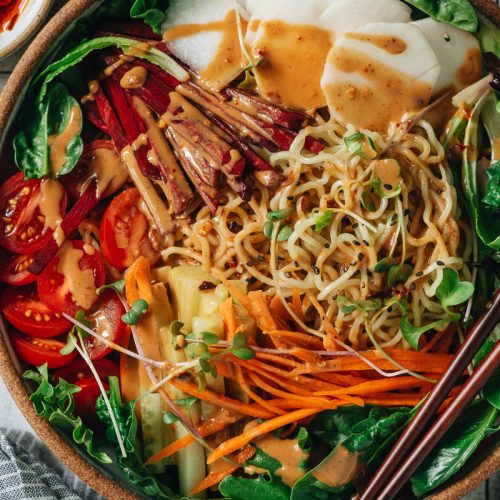 A bowl of noodles and colorful veggies with sesame sauce (vegan)