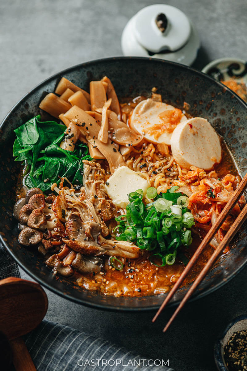 Vegan kimchi ramen in a black bowl with tofu, mushrooms, and bamboo