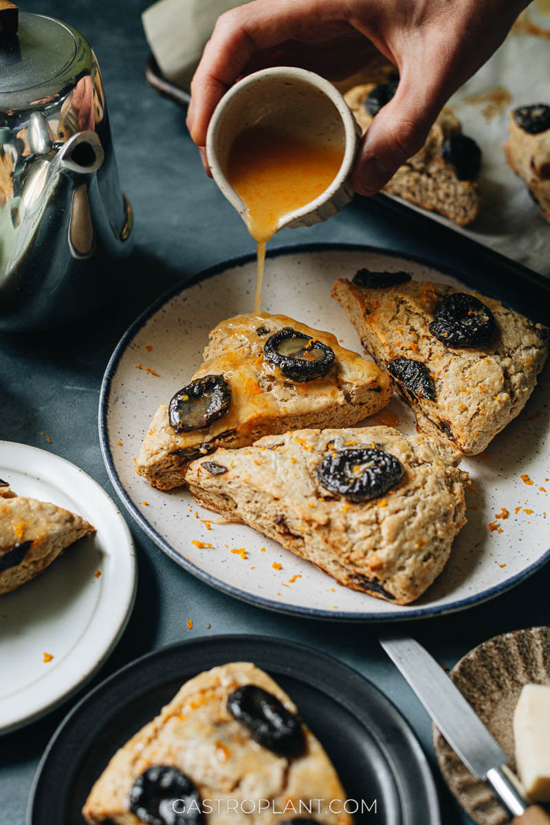 Drizzling orange glaze onto a prune pastry